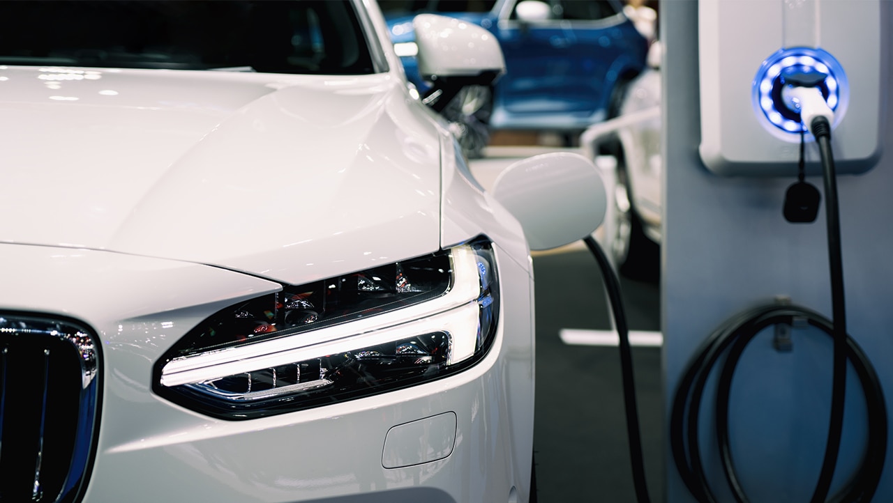 Close up view of a car’s headlights while plugged into an electric vehicle charging point.
