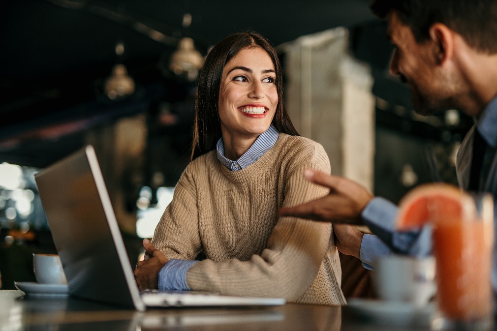 Two professionals talking in front of laptop