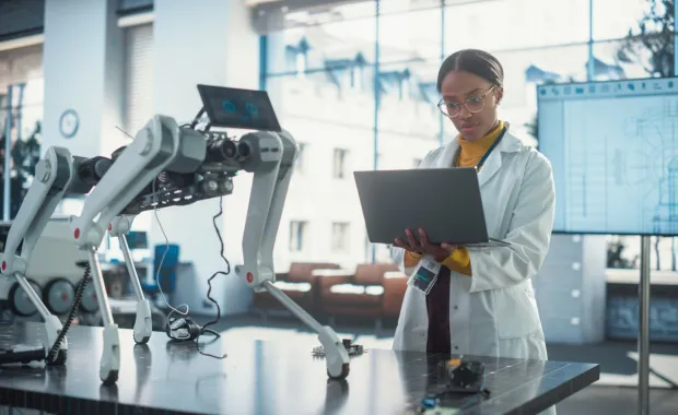 Specialist in lab using laptop to test an AI robotic