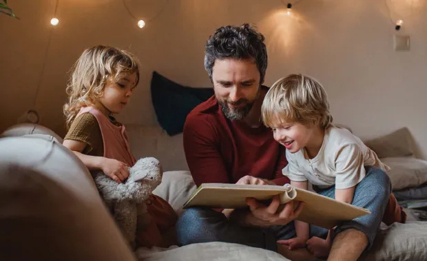 An adult reading to 2 children