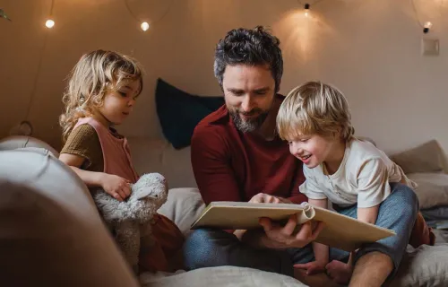 An adult reading to 2 children