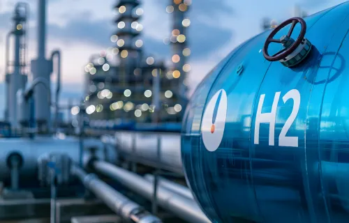 Hydrogen storage tank at an industrial site with pipelines and refinery in the background.