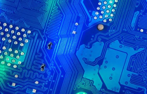 Närbild av ett blått kretskort med elektroniska banor och lödpunkter.