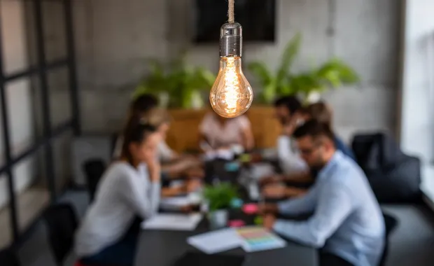 light bulb in front of innovation team meeting