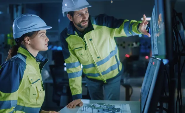 Project engineer talks to operator who controls facility production line