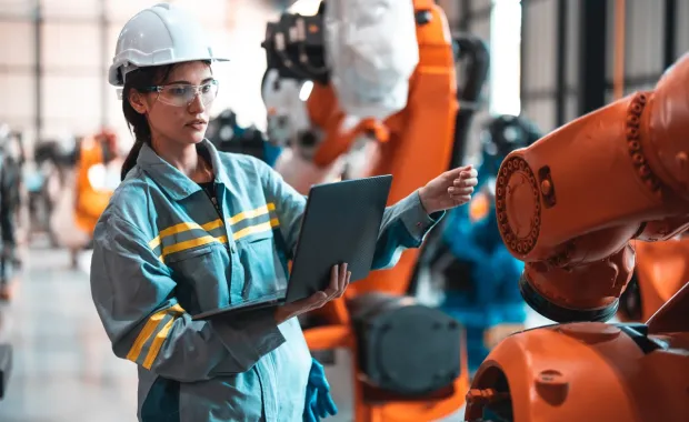 Robotic engineer using laptop for robot maintenance