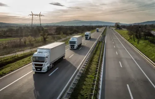 Transport vehicles on a highway with a sunset in the background