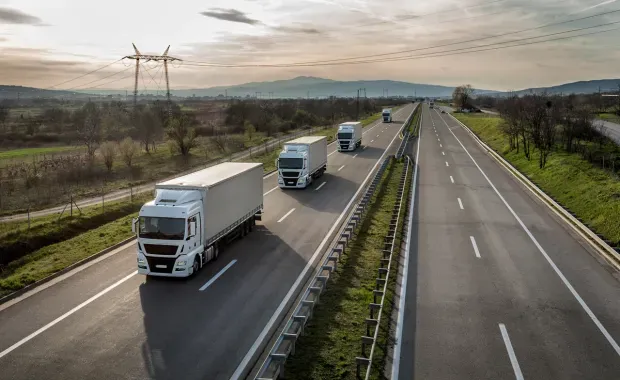 Transport vehicles on a highway with a sunset in the background