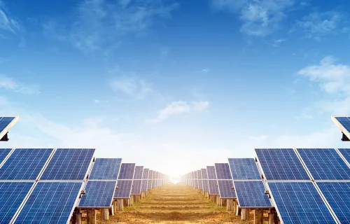 Päikesepaneelid põllul, eemal päike ning pilved